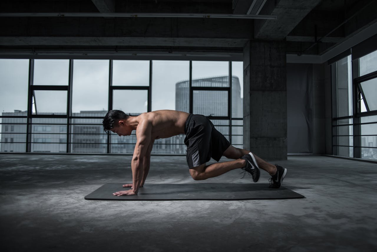our-services-1 Fit man doing mountain climbers exercise inside a modern gym
